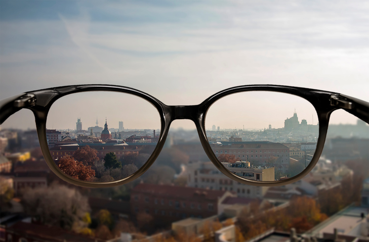 Myopie - neostré vidění do dálky - rozmazaná kulisa města a brýle s ostrým viděním
