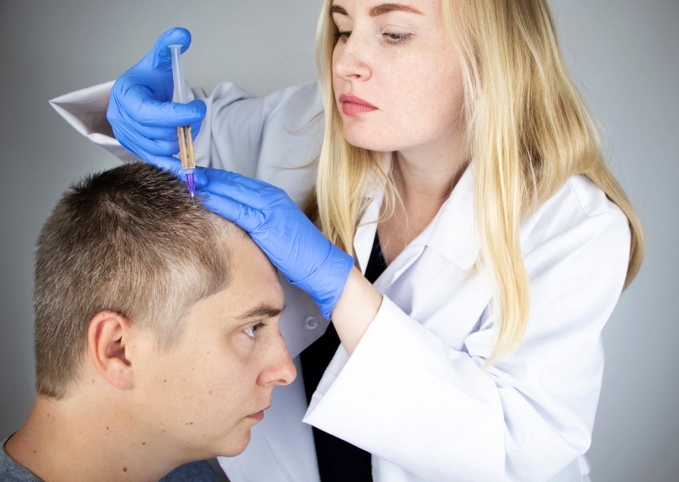 Léčba vypadávání vlasů, lékařka dávkuje injekčně lék do hlavy pána, pacienta