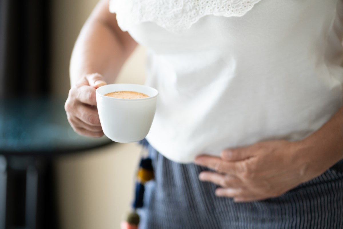 Šálek kávy v ruce člověka, jako rizikový faktor zhoršení projevů refluxu