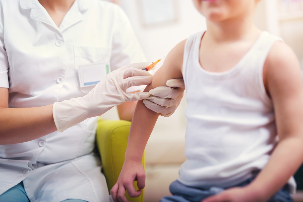 Očkování dítěte - lékař očkuje dítě - dítě sedí a lékař mu dá injekci do ramene.