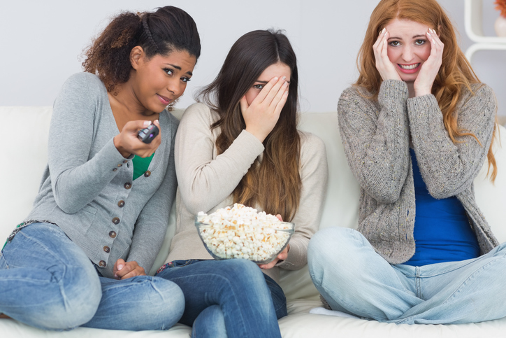 Tři dívky mají strach, dívají strašidelný film, popcorn v misce