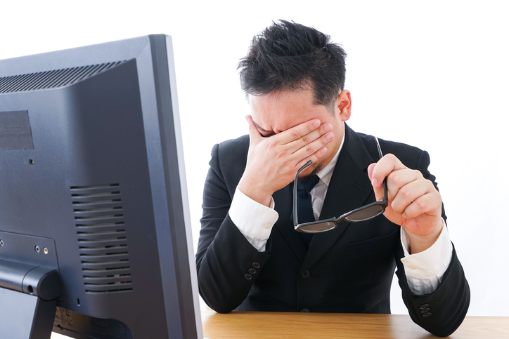 Muž pracující za počítačem má syndrom suchého oka a unavené oči