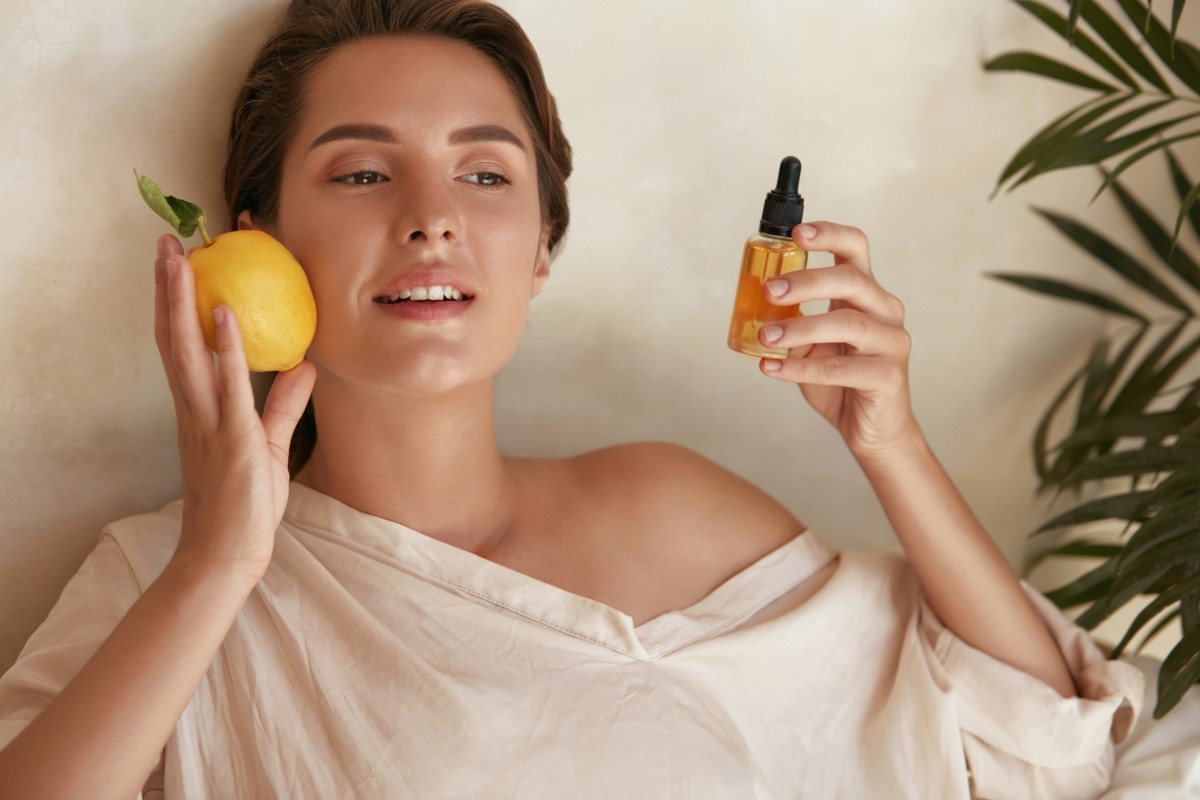 Žena s citronem a lahvickou s výtažkem vitamínu C v ruce, vitamín, který pomáhá pokožce