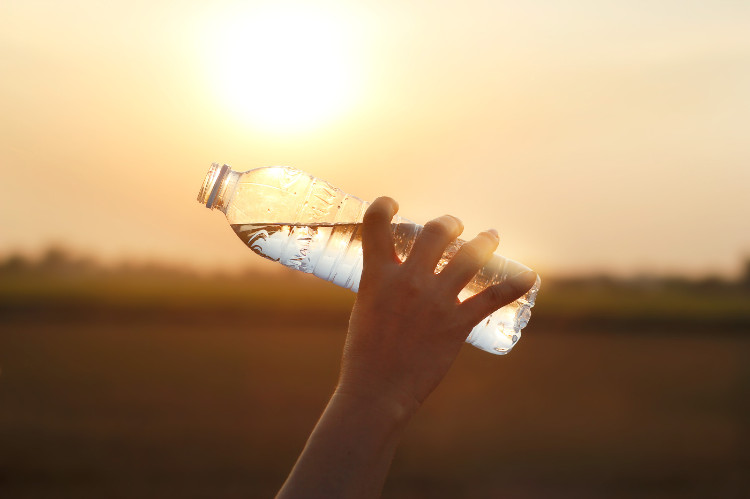 ruka držící lahvičku s vodou