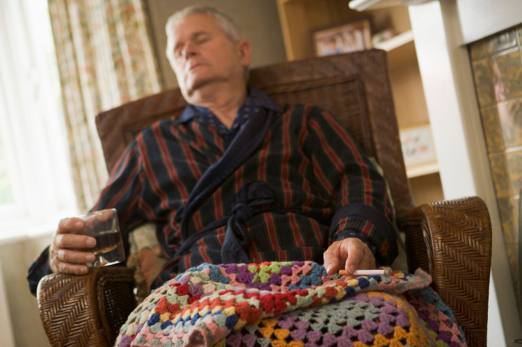 spící dědeček v křesle přikrytý dekou, v ruce má sklenici s alkoholem a cigaretu