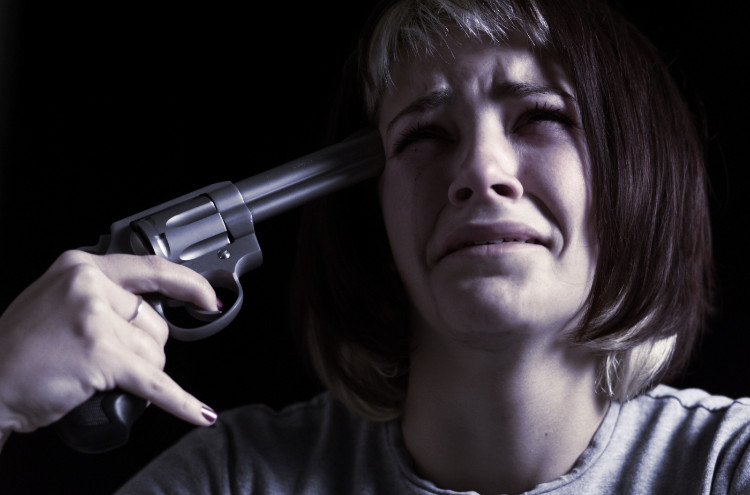 plačící žena si drží pistoli namířenou k hlavě