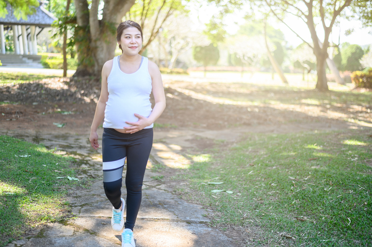 Těhotná žena na procházce parkem.