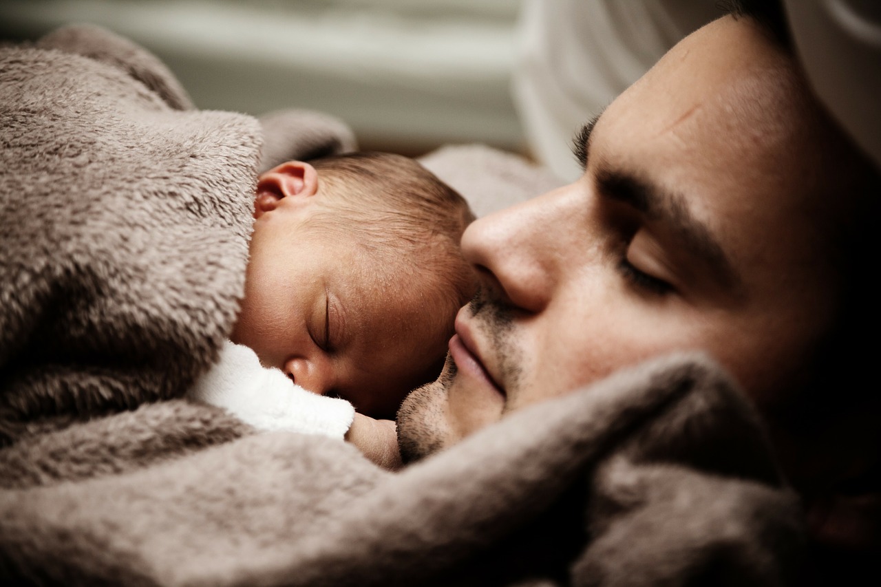 děťátko spí vedle otce pod hnědou dekou