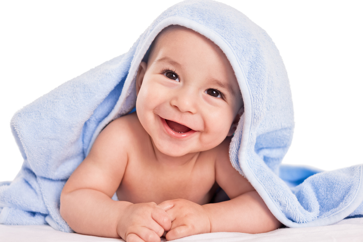 vysmáté dítě na bříšku, přikryté ručníkem