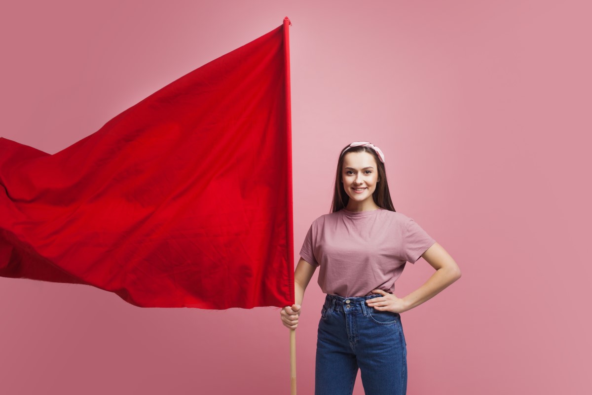 Žena drží velkou červenou vlajku jako varování.