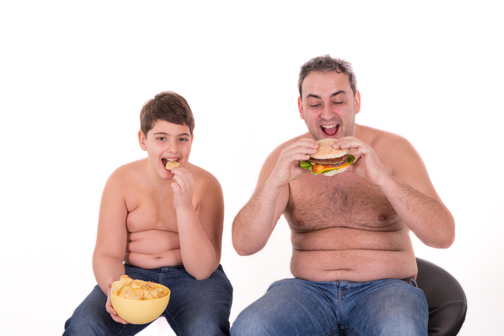 chlapec a táta se nesprávně stravují, jedí hamburger, jsou obézní