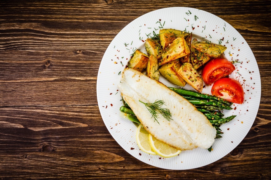 Příklad večeře: grilovaná ryba s chřestem, pečenými brambory, bylinkami a čerstvou zeleninou.