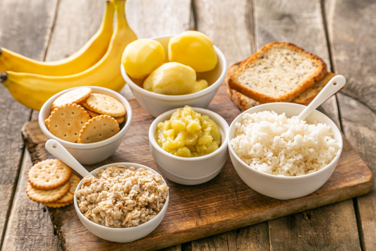 Příklad vhodné stravy při akutním průjmu - rýže, brambory, banány, sušenky, krekry, v miskách a na dřevěném prkénku.