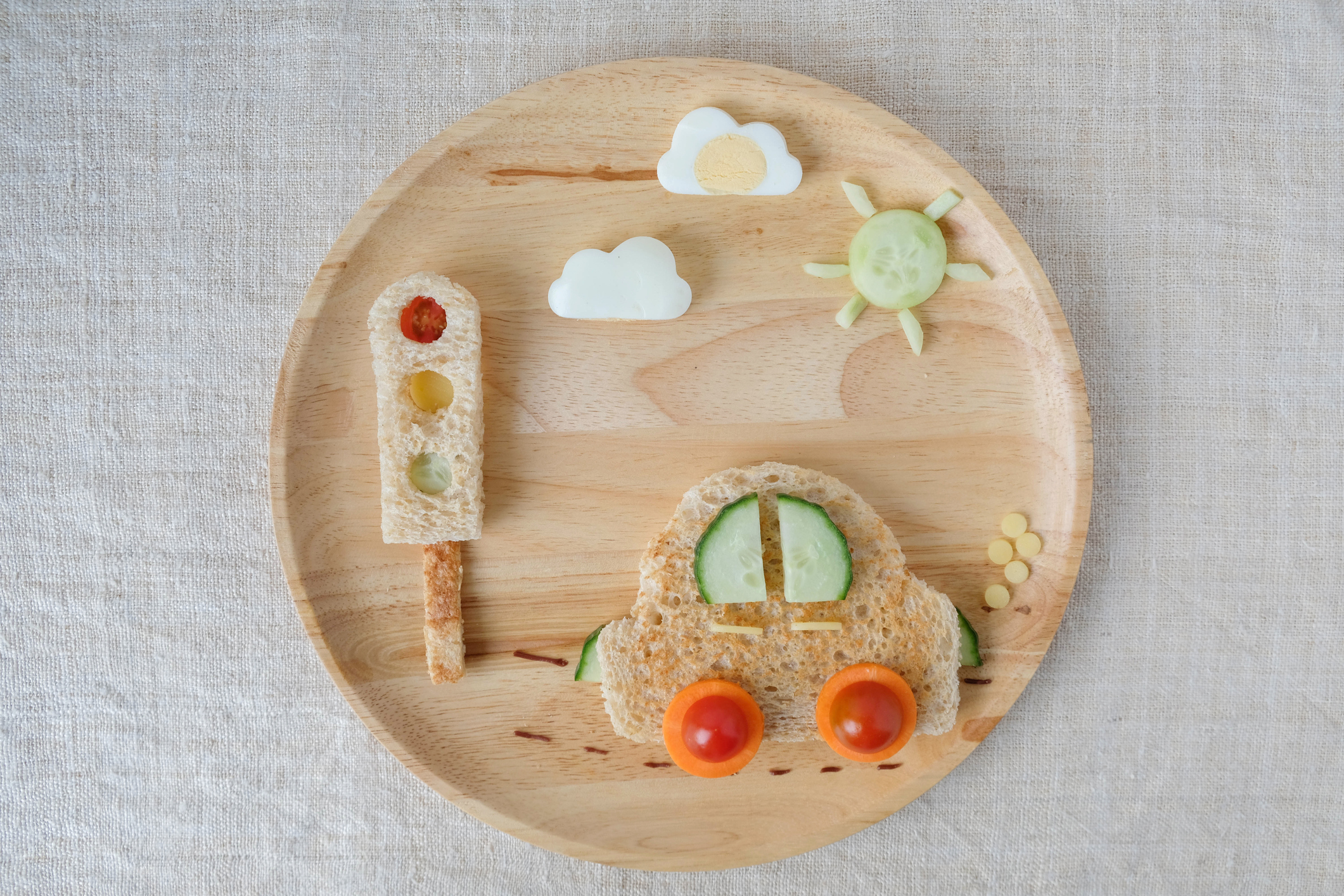 Lehké občerstvení na talíři ve tvaru autíčka. Rajčata, mrkev, okurka, chleba, vejce
