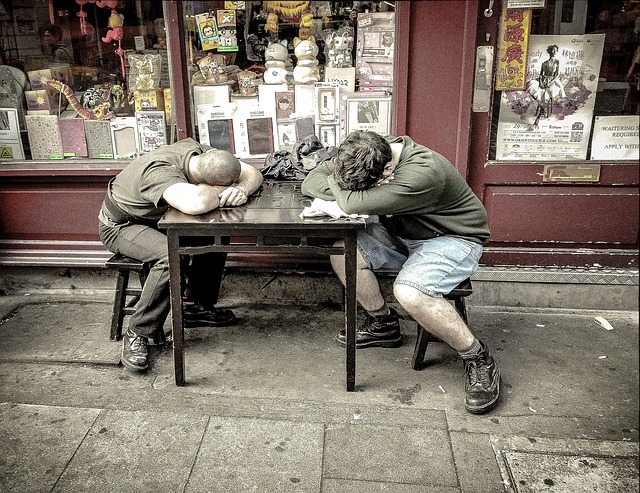 Dva muži spí za stolem před obchodem. Je to starý obchod.