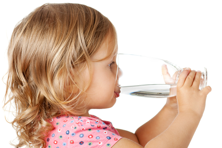 Malá holčička pije čistou vodu ze sklenice