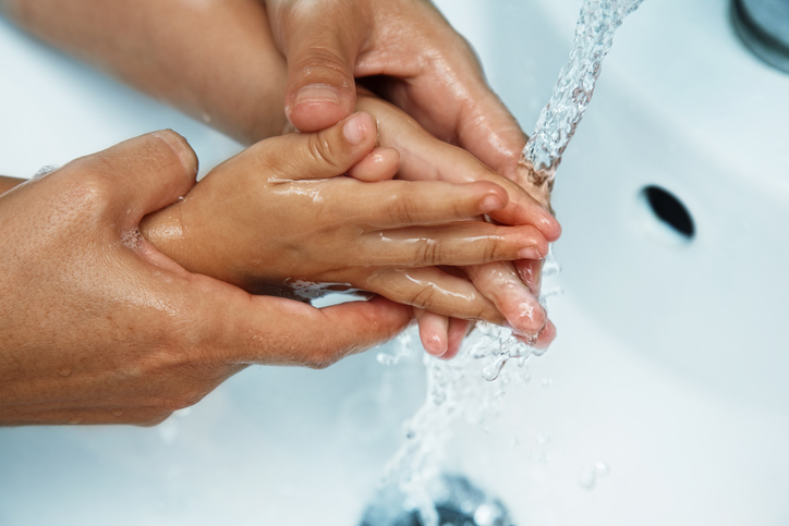 ruce matky nad umyvadlem myjí dětské ruce pod tekoucí vodou