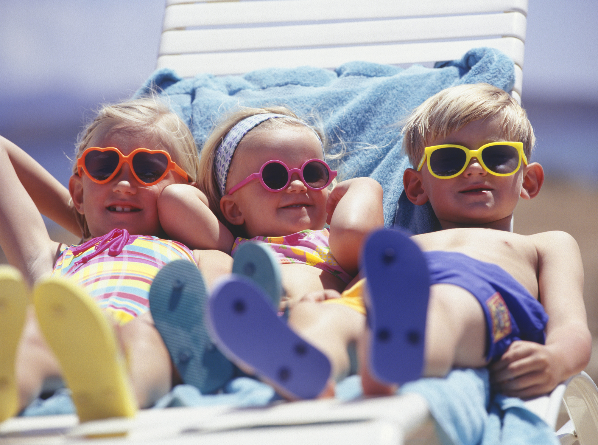 Tři děti na lehátku ve slunečních brýlích