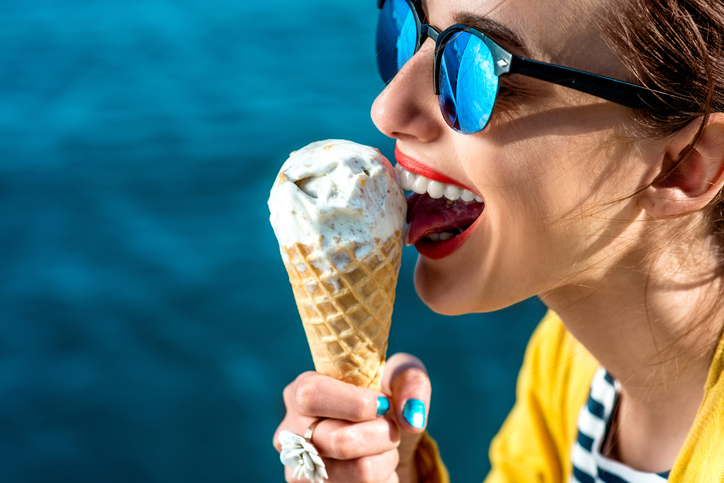 žena ve slunečních brýlích líže zmrzlinu vedle vody