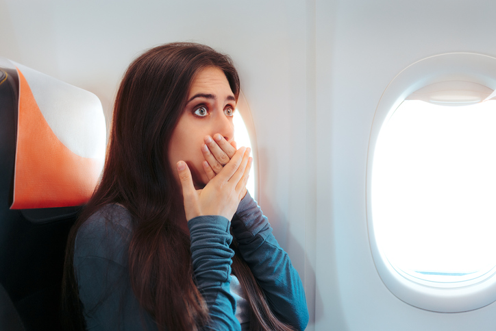 žena sedící v letadle u okna, chce se jí zvracet