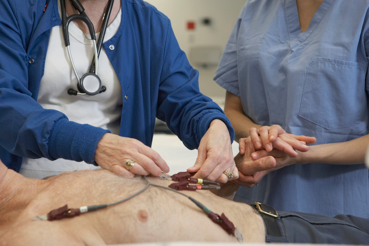 EKG vyšetření muže, elektrody na hrudi, vyšetřují ho dvě lékařky