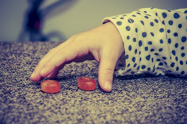 Dětská ruka, dva červené bonbóny, špatné stravovací návyky