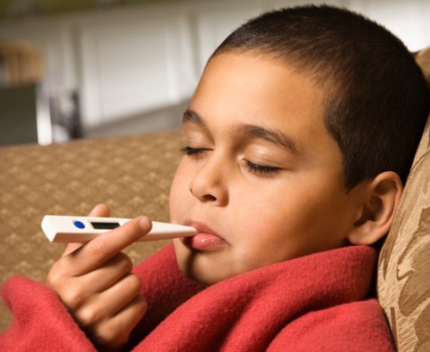 Dítě si měří tělesnou teplotu digitálním teploměrem v ústech