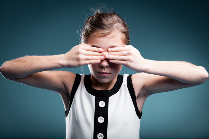 mladá dívka si zakrývá oči jako náznak slepoty