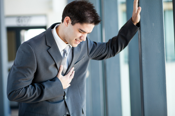 Mladý muž, byznysmen má potíže, bolesti na hrudi, možná má infarkt srdečního svalu nebo je pracovně přetížen