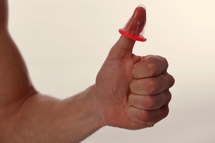 Muž drží na prstu, tedy na palci kondom, jako symbol ochrany před pohlavně přenosnými onemocněními a před oplodněním vajíčka spermií
