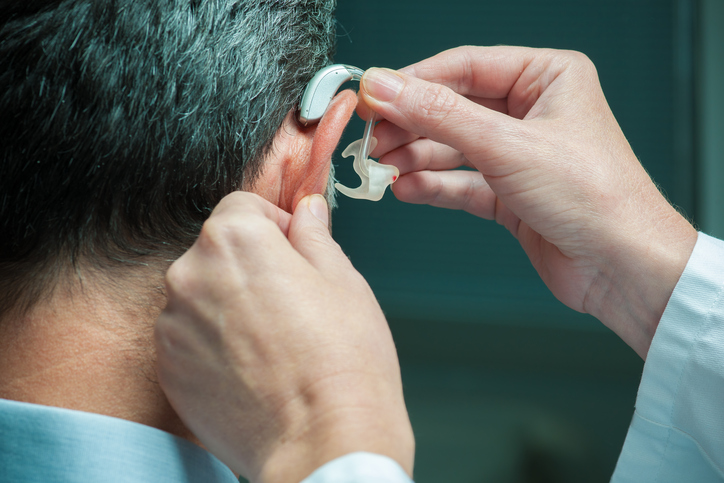 muži aplikují naslouchací aparát na ucho