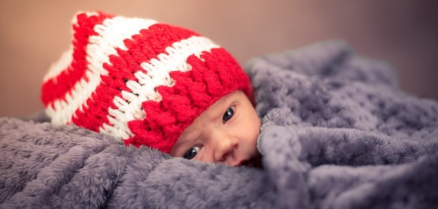 Dítě, leží zakryté, v červenobílé pruhované čepici
