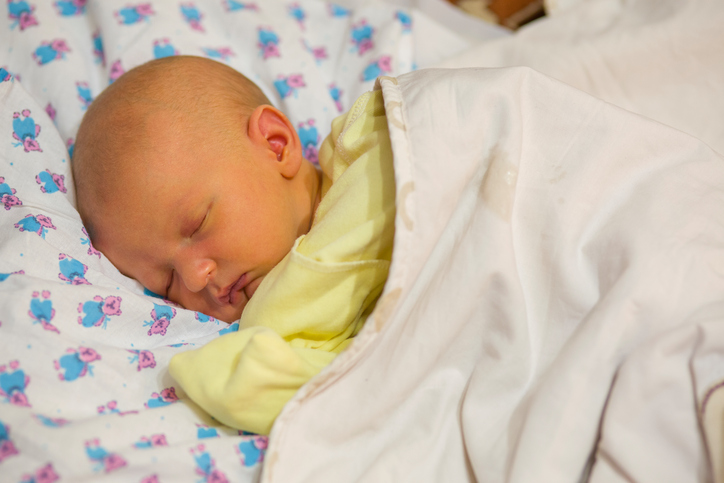Novorozenec, leží v postýlce, oblečený, zakrytý, novorozenecká žloutenka, nažloutlá kůže