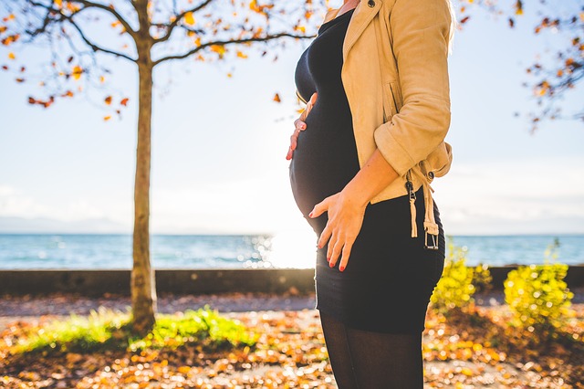 těhotná žena stojí před stromem podzim