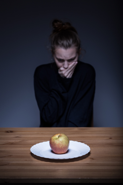 Žena odmítá jídlo, na talíři je jablko, nechutenství