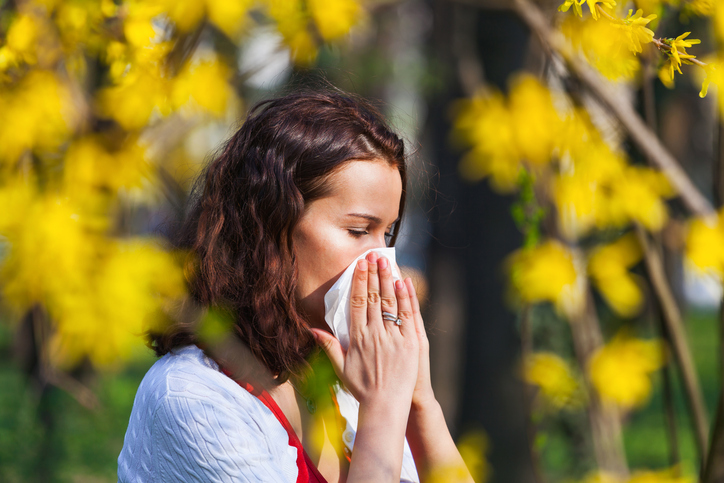 Žena si fouká ucpaný nos pro sennou rýmu, tedy alergii na pyl
